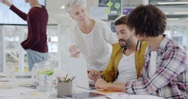 Modern bir açık plan ofisinde dizüstü bilgisayarla konuşan çeşitli yaratıcı profesyonellerin yan görüntüsü.