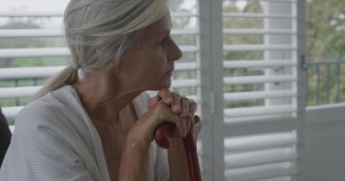 Bir baston yaslanmış düşünceli bir üst düzey Kafkas kadının yan görünümü yakın