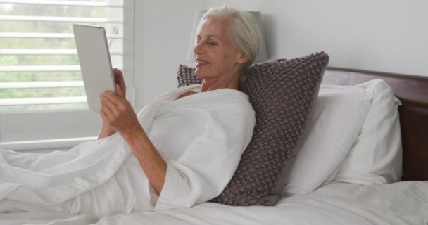 ベッドに横たわり タブレットコンピュータを使用した白人女性の側面図 — ストック動画