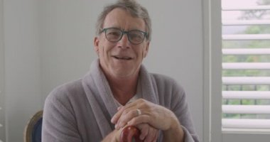 Okuma gözlüğü takan ve bastona yaslanmış gülümseyen kıdemli beyaz bir adamın portresi