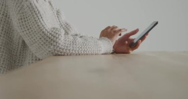 Akıllı telefon kullanarak masada oturan genç bir kadının yan görünümü orta bölümü