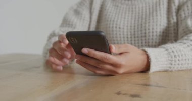 Akıllı telefon kullanarak masada oturan genç bir kadının ön görünümü orta bölümü