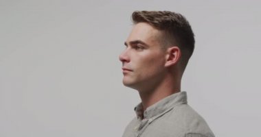 Side view close up of a young Caucasian man looking straight ahead, blinking and breaking into a smile