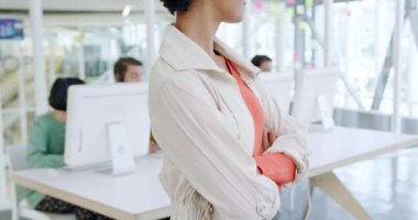 Gülümseyen, genç, melez, yaratıcı, kısa kıvırcık saçlı ve modern açık plan ofisinde gülümseyen bir iş kadınının portresi. Arka planda bilgisayarlarda çalışan meslektaşları.