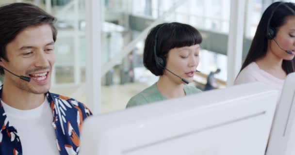 一组年轻的多族裔呼叫中心工作人员头戴耳机 在一个现代开放式计划办公室里使用电脑 侧面观照 — 图库视频影像