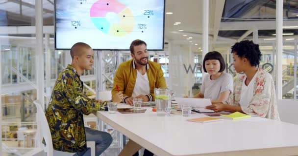 Vue de face d'un groupe de jeunes professionnels de la création multiethnique assis autour d'une table discutant lors d'une réunion dans un bureau moderne à aire ouverte 