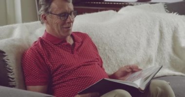 Kanepede oturan ve bir fotoğraf albümüne bakan düşünceli bir Kafkasyalı 'nın ön görüntüsü.