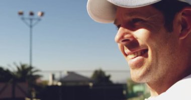 Güneşli bir günde tenis maçı sırasında gülümseyen beyaz bir adamın yakından görünümü