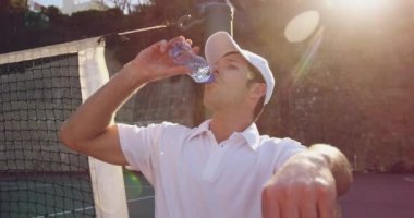 Tenis oyununda bir mola sırasında su içen genç bir Kafkas adamın ön görünümü yakın