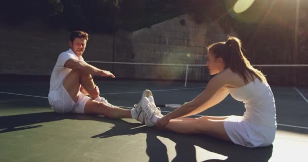 若い白人女性と若い白人男性がコートでテニスをし 試合前にストレッチして話している側見 — ストック動画