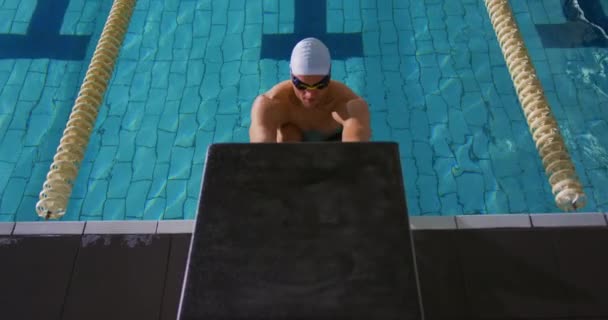 スイミングプールで若い白人男性水泳選手のトレーニングの正面図 壁を押し出す — ストック動画