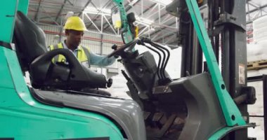 Bir depo yükleme koyunda bir forklift kamyon üzerine tırmanma orta yaşlı karışık ırk erkek depo işçisi yan görünümü yakın
