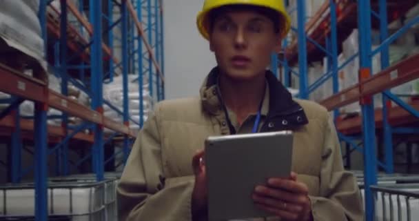 Vue de face gros plan d'une jeune gérante d'entrepôt caucasienne utilisant une tablette et inspectant des étagères dans un entrepôt de stockage 