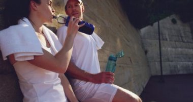 Tenis oyununda bir mola sırasında genç bir Kafkas kadın ve genç bir Kafkas adam içme su yan görünümü