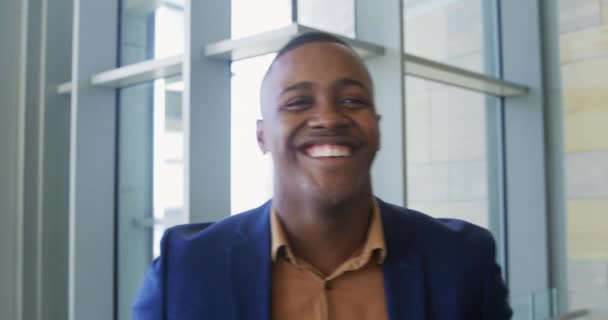 一位年轻的非洲裔美国商人站在一幢现代办公大楼的大堂里 面带微笑地对着摄像机笑 这幅肖像非常逼真 — 图库视频影像