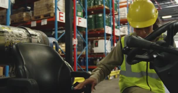 タブレットコンピュータを使用して若い混合レース女性倉庫労働者のフロントビューを閉じる倉庫荷室内のフォークリフトトラックに登る — ストック動画
