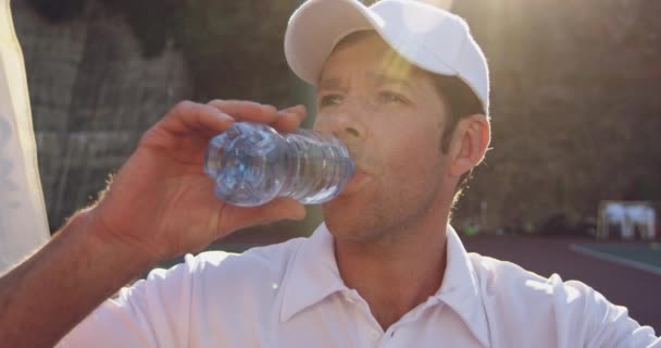 テニスの試合で休憩中に水を飲む若い白人男性の正面図クローズアップ — ストック動画