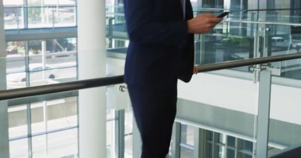現代的なオフィスビルのロビーに立って スマートフォンと笑いを使用して若い白人実業家の正面図 — ストック動画