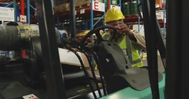 中年の混合人種の男性倉庫労働者のフロントビューのクローズ倉庫荷室内のフォークリフトトラックにクリップボードを保持 — ストック動画