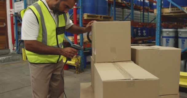 中年の混合人種の男性倉庫労働者のサイドビューを閉じる倉庫荷室内のバーコードリーダで箱のラベルをスキャンし 箱を持ち去る — ストック動画