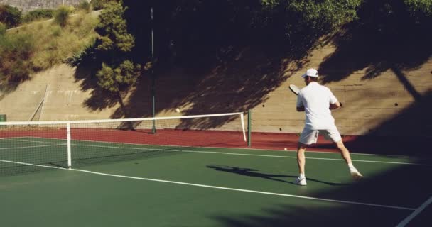 一个年轻的白种人男子在阳光明媚的日子打网球 返回一个球的侧视图 — 图库视频影像