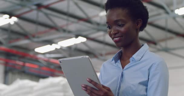 前视图特写一个微笑的年轻混血女性仓库经理使用平板电脑在存储仓库 — 图库视频影像