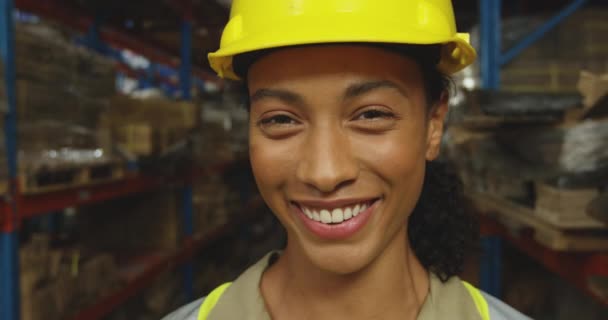 一名年轻的混血女仓库工人头像照片 戴着一顶黄色硬礼帽 面带微笑地在仓库里拍照 — 图库视频影像