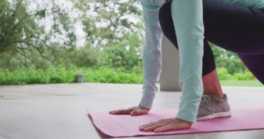 Bahçede yoga uygulayan üst düzey bir Beyaz kadının yan görünümü