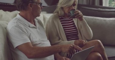 Üst düzey bir Beyaz kadın ve adam bir kanepede oturan ve bir tablet bilgisayar kullanarak yan görünümü yakın