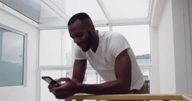 Evde akıllı telefon kullanarak gülümseyen genç yetişkin karışık Yarış adam ön görünümü yakın