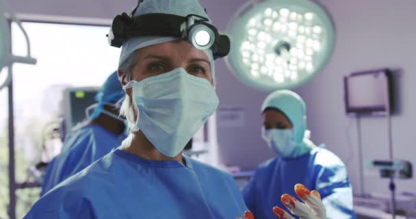 Nahaufnahme einer kaukasischen Chirurgin, die im Operationssaal eines Krankenhauses steht. sie schaut auf kamera, video 