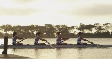 Nehirüzerinde yarış kabuğunda kürek çekerek kürek çekerek dört genç yetişkin Kafkas kadınından oluşan bir takımın yan görünümü