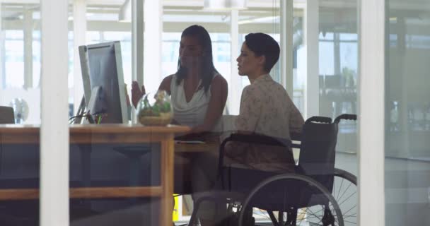車椅子で創造的な若い白人女性のビジネスと現代のオフィスで創造的な若い混合人種の女性のビジネスの側面ビュー コンピュータを使用して — ストック動画