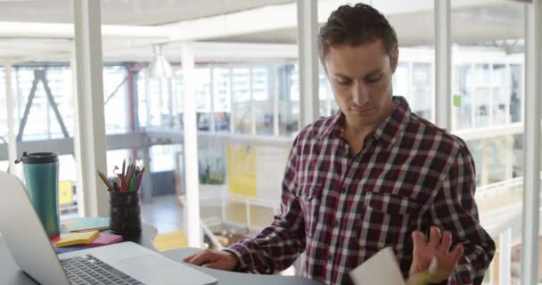 在现代办公室里工作 使用笔记本电脑并做笔记的快乐的年轻白种人男性生意的前景色 — 图库视频影像