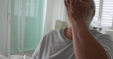 Su ile bir hap alarak olgun bir karışık ırk adam ön görünümü yakın