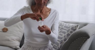 Evde tablet bir şişe geri olgun bir karışık ırk kadın ön görünüm yakın