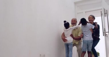 Evde kollarında kendi küçük torunları tutan olgun bir karışık ırk çift ön görünüm yakın