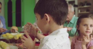 Beyaz bir ailenin portresi. Üç nesildir evde bir masada oturuyor ve yemek yiyor.