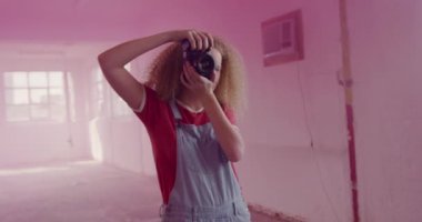 Boş bir depoda bir kalça genç Kafkas kadın ön görünümü, bir el bombası pembe duman ile çevrili fotoğraf çekmek