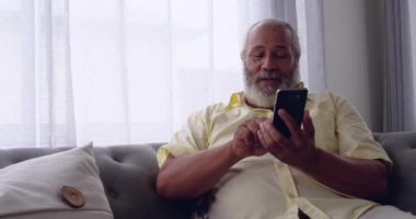 Evde bir telefon görüşmesi yapmak bir kanepede oturan gülümseyen olgun karışık Yarış adam ön görünümü yakın