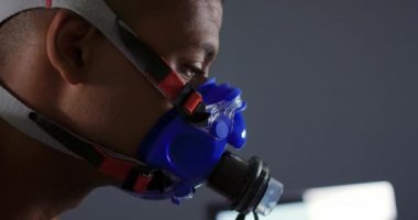 Eğitim sırasında metabolik gaz analizörü kullanan, yüz maskesi takan genç bir karışık ırk erkek bisikletçinin yan görünümü