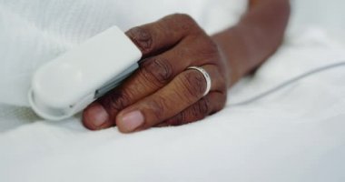 Hastanede koğuşta Afro-Amerikan erkek hasta elinde Pulse oksimetri yakın çekim. O yatakta yatıyor, video