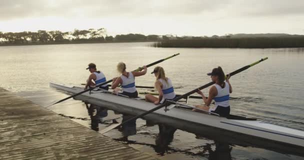一支由四名年轻的成年白种妇女组成的团队 在训练前用桨将船从码头上推开 — 图库视频影像