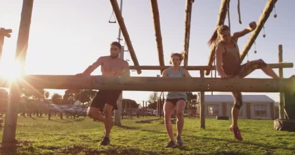 ブートキャンプのトレーニングセッション中に屋外ジムでハードルを越えてボールトをする2人の若い白人女性と若い白人男性の正面図 — ストック動画