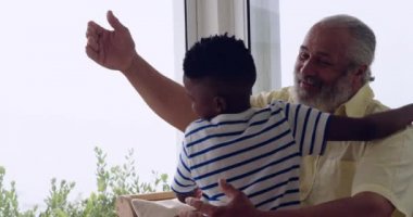 Genç torununa sarılan ve onunla gülen olgun bir karışık ırk adam ön görünümü yakın