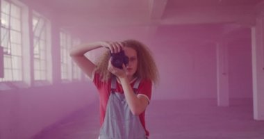 Boş bir depoda bir kalça genç Kafkas kadın ön görünümü, bir el bombası pembe duman ile çevrili fotoğraf çekmek