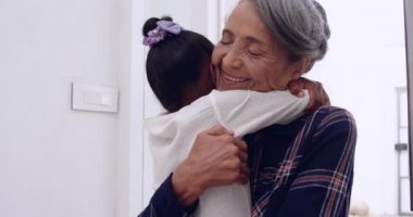 Olgun bir karışık ırk kadın kollarında genç torunu tutan ve evde ona sarılma ön görünümü yakın