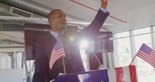 米国の旗で飾られた表彰台に立つアフリカ系アメリカ人男性の笑顔のビデオ — ストック動画