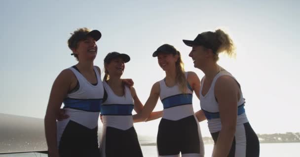 川のそばのカメラに微笑み合うチームカラーを身に着けた4人の若い大人の白人女性の漕ぎ手の肖像画 — ストック動画