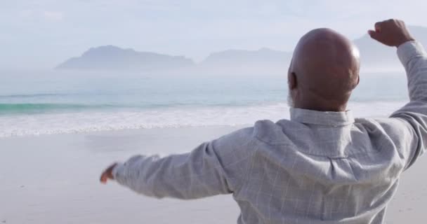 后视特写一个成熟的混血儿男子在海边的海滩上欢快地击打空气 — 图库视频影像